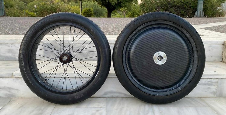 An aluminium spoked rim and the new one-piece carbon-fibre wheel, tyres fitted, standing side by side