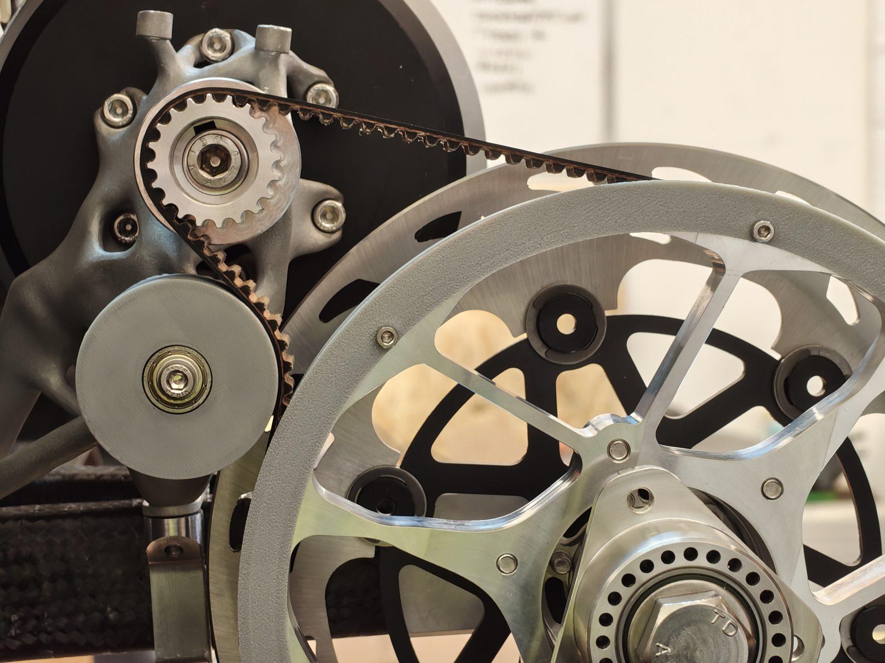 PYRFOROS IV's belt drivetrain installed on the car: motor-side toothed pulley, toothed belt, and the driven hub