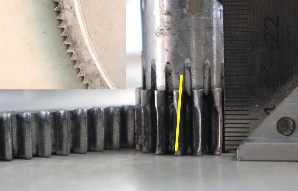 Macro photo of gear teeth worn from angular misalignment, with the wear angle annotated